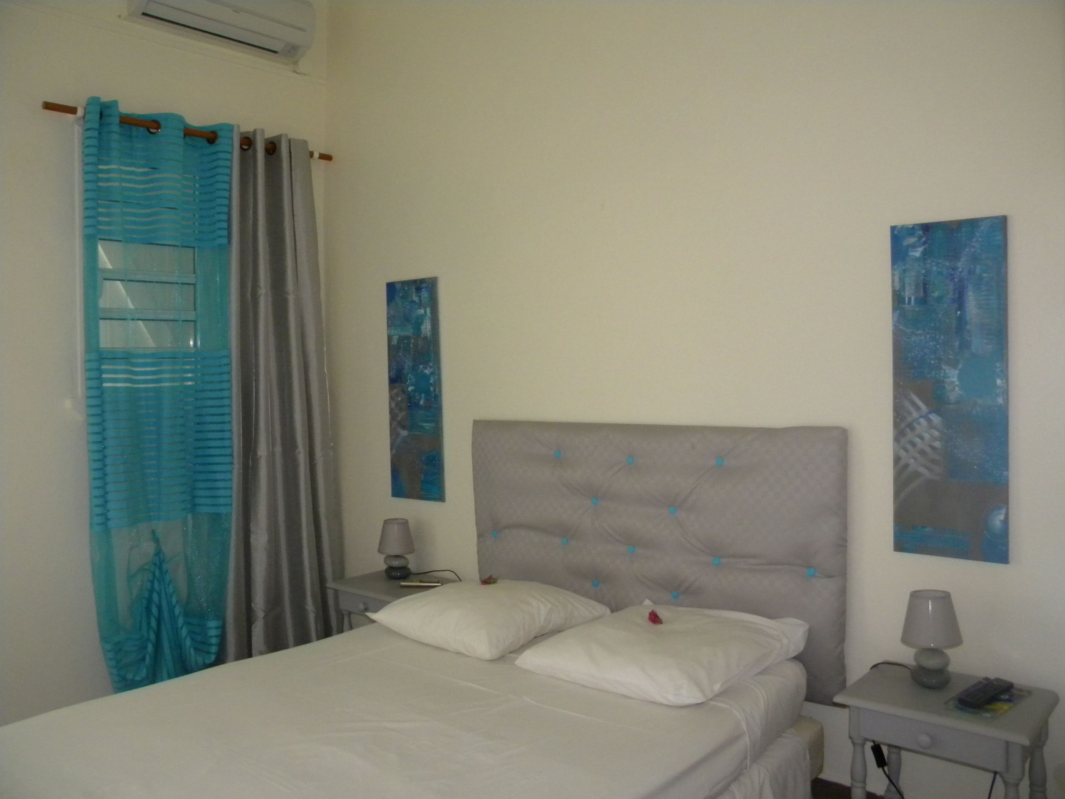 Un dormitorio con cama, mesita de noche y dos lámparas de pared.