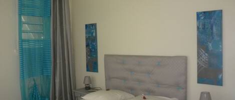 Un dormitorio con cama, mesita de noche y dos lámparas de pared.