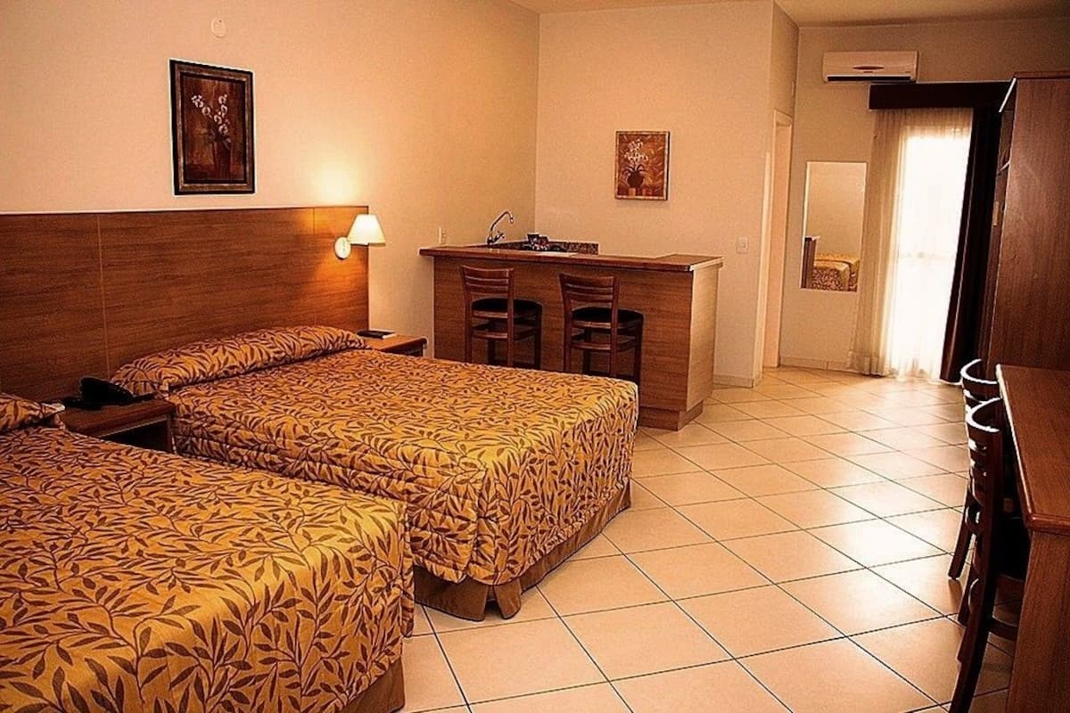 A hotel room with two beds, a desk, and a chair.
