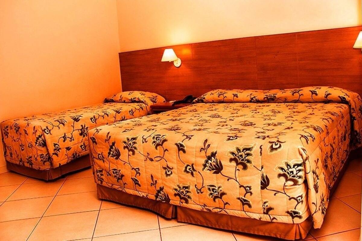 A double bed with a wooden headboard, two bedside tables, and a floral-patterned bedspread.