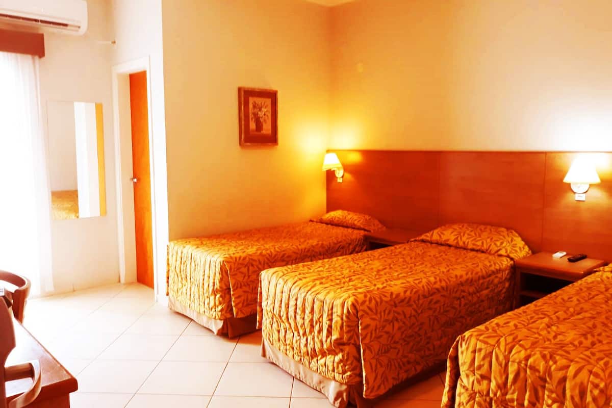 A hotel room with two beds, a desk, and a chair.
