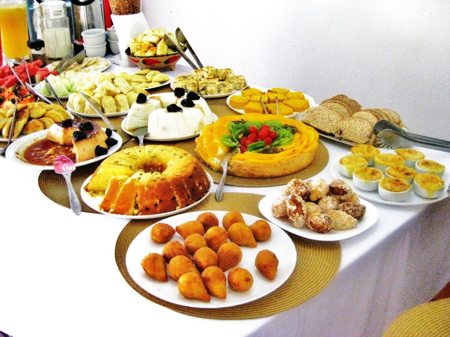A buffet table with various dishes including a bundt cake, fruit, pastries, and bread.