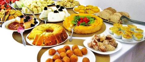 A buffet table with various dishes including a bundt cake, fruit, pastries, and bread.