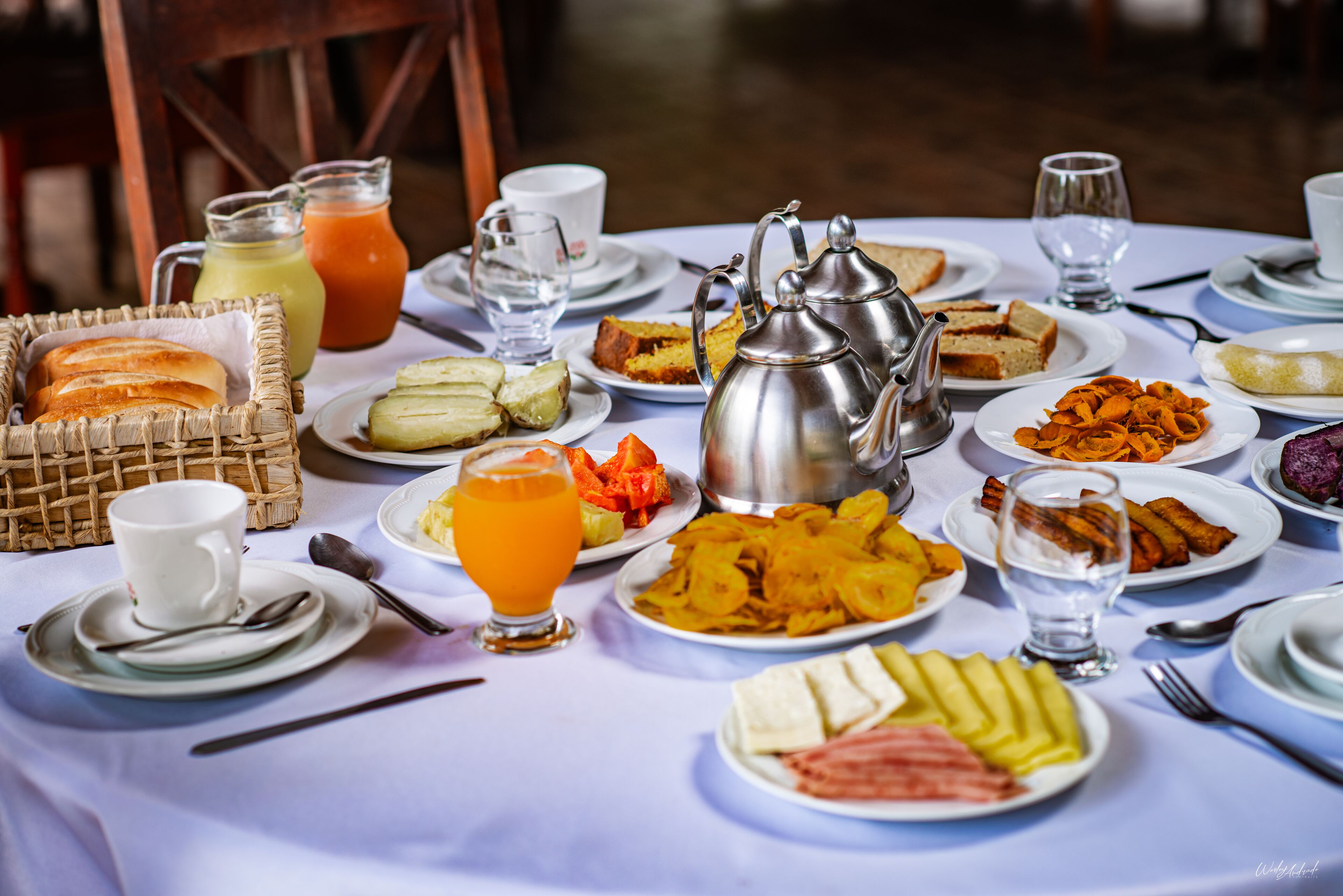 Une table dressée avec des aliments pour le petit-déjeuner, notamment du pain, des fruits et des boissons.