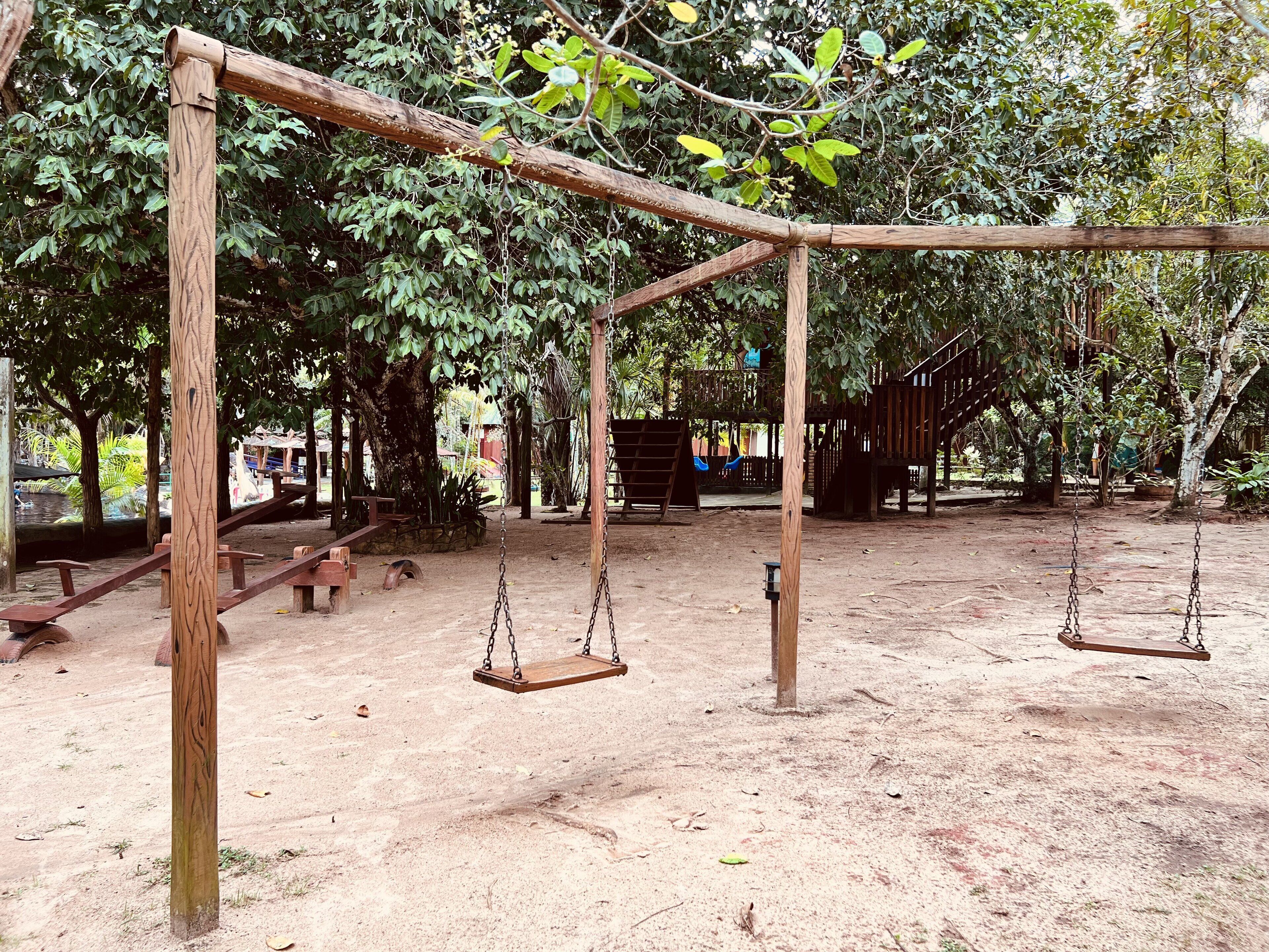 A playground with swings and a wooden structure.