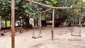 A playground with swings and a wooden structure.
