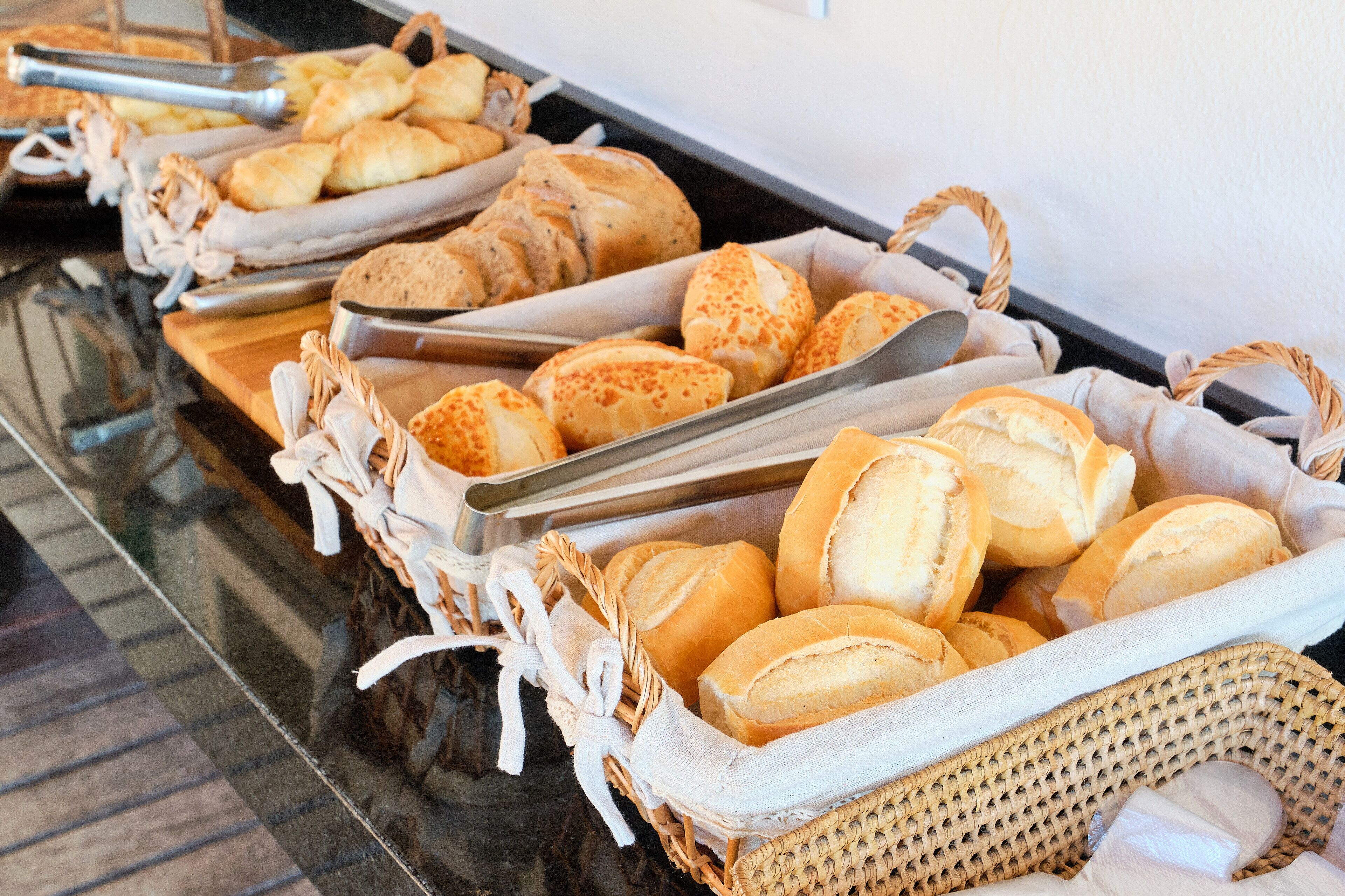 A buffet table with various breads and pastries in baskets.