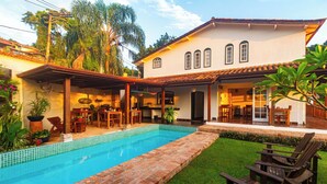 A poolside area with a tiled pool, wooden deck, and outdoor furniture.