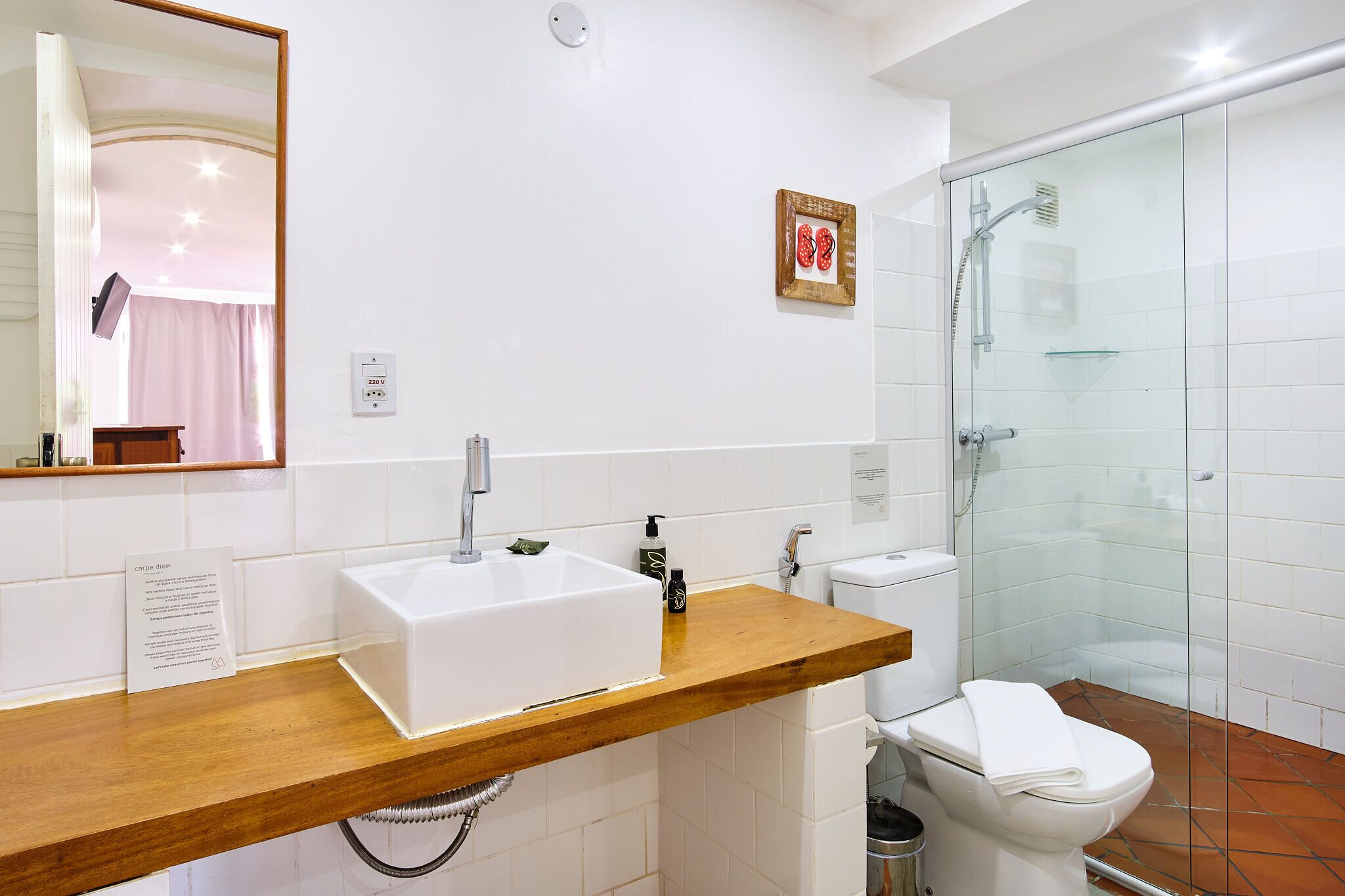 A bathroom with a white sink, wooden countertop, white toilet, and a glass shower enclosure.