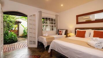 Habitación de hotel con dos camas, una ventana con cortinas, un espejo y una mesita de noche con lámpara.