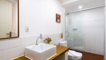 A bathroom with a white sink, a wooden countertop, a glass shower enclosure, and a white toilet.