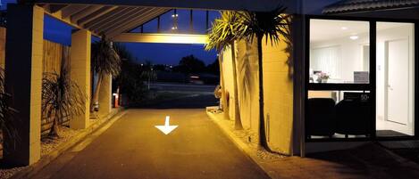 L’entrée d’un hôtel, avec un panneau « STOP » sur le trottoir, une allée couverte et une entrée de bâtiment avec un panneau « DÉFENSE DE FUMER ».