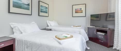 A hotel room with two beds, a TV, and framed pictures on the wall.