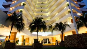 Un hôtel de grande hauteur doté de nombreux balcons, d’un atrium central et de palmiers.