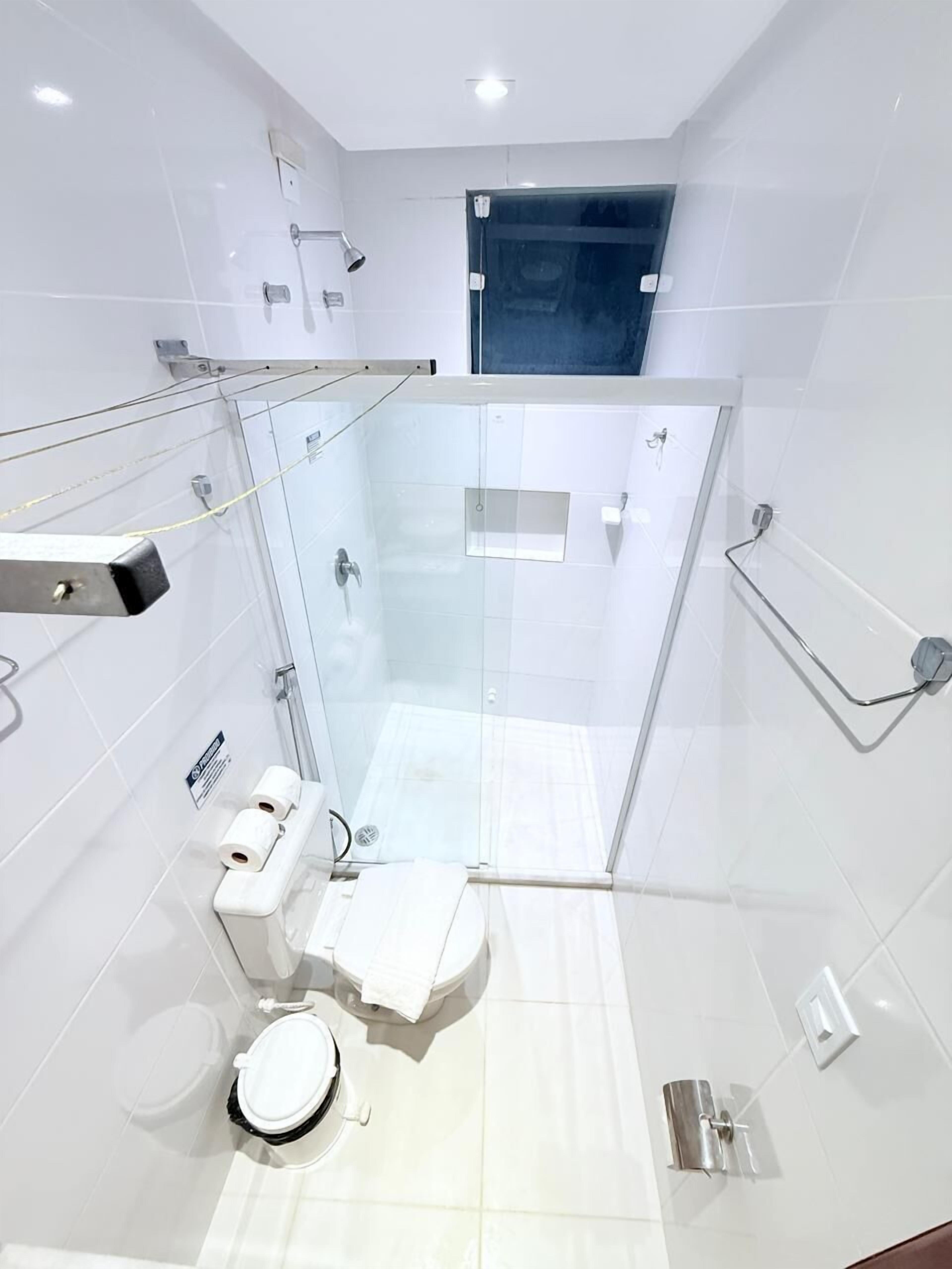 Een moderne badkamer met een glazen douchecabine, toilet en een hygiëneschuimer.