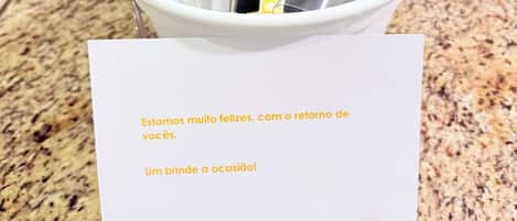 A bucket with a bottle of champagne and glasses, a note with a message, and a granite countertop.
