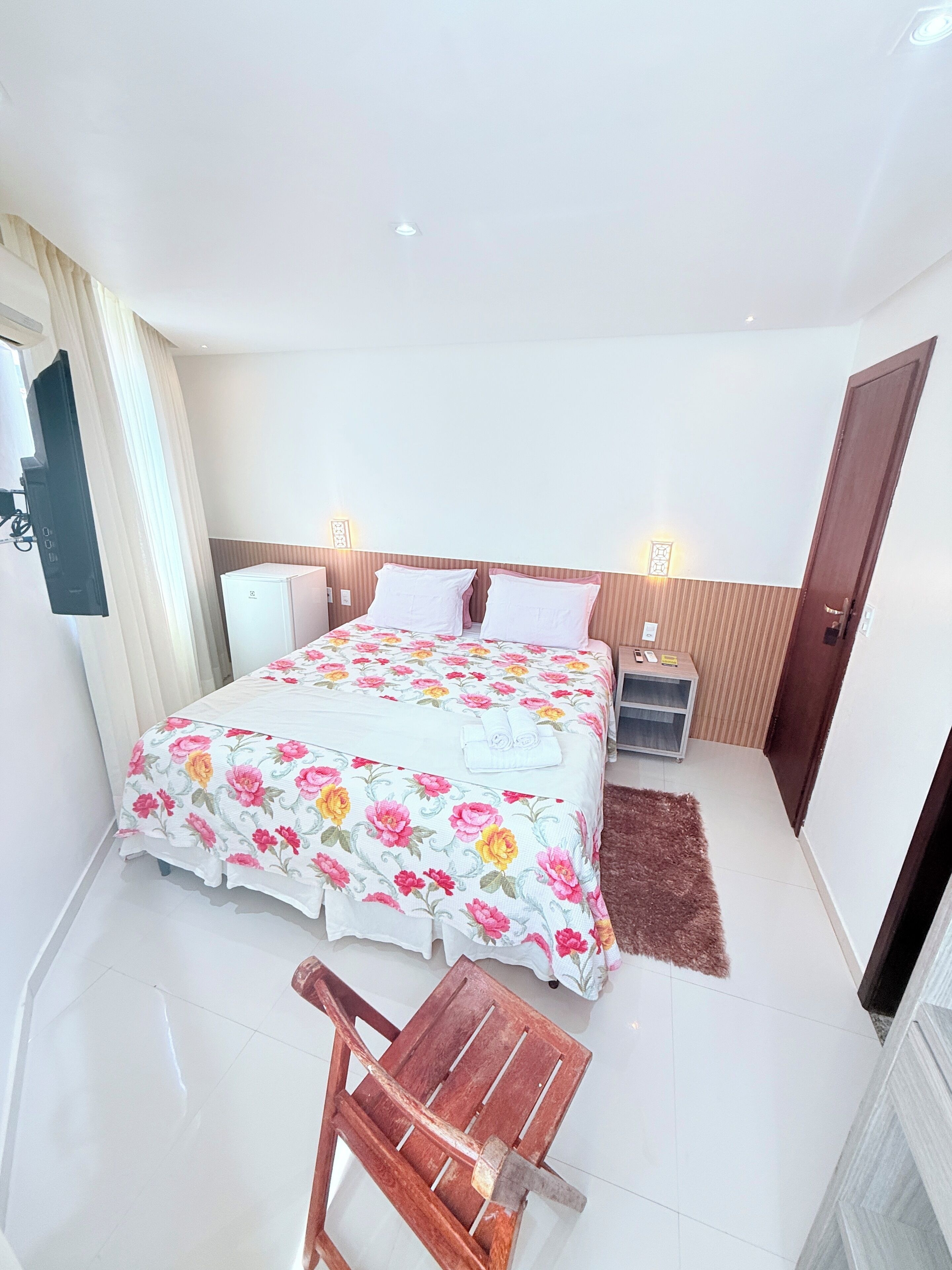 A bedroom with a bed, bedside tables, a chair, and a wardrobe.