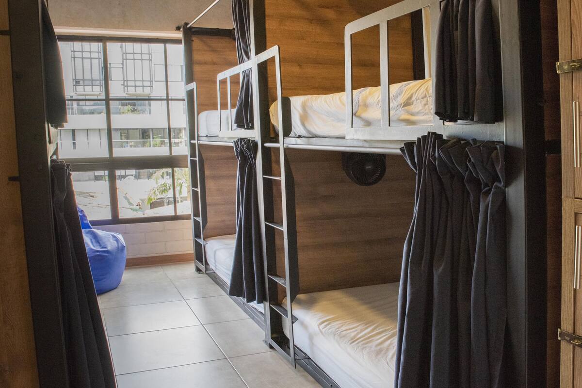 A dormitory room with bunk beds, a window, and a blue bean bag chair.