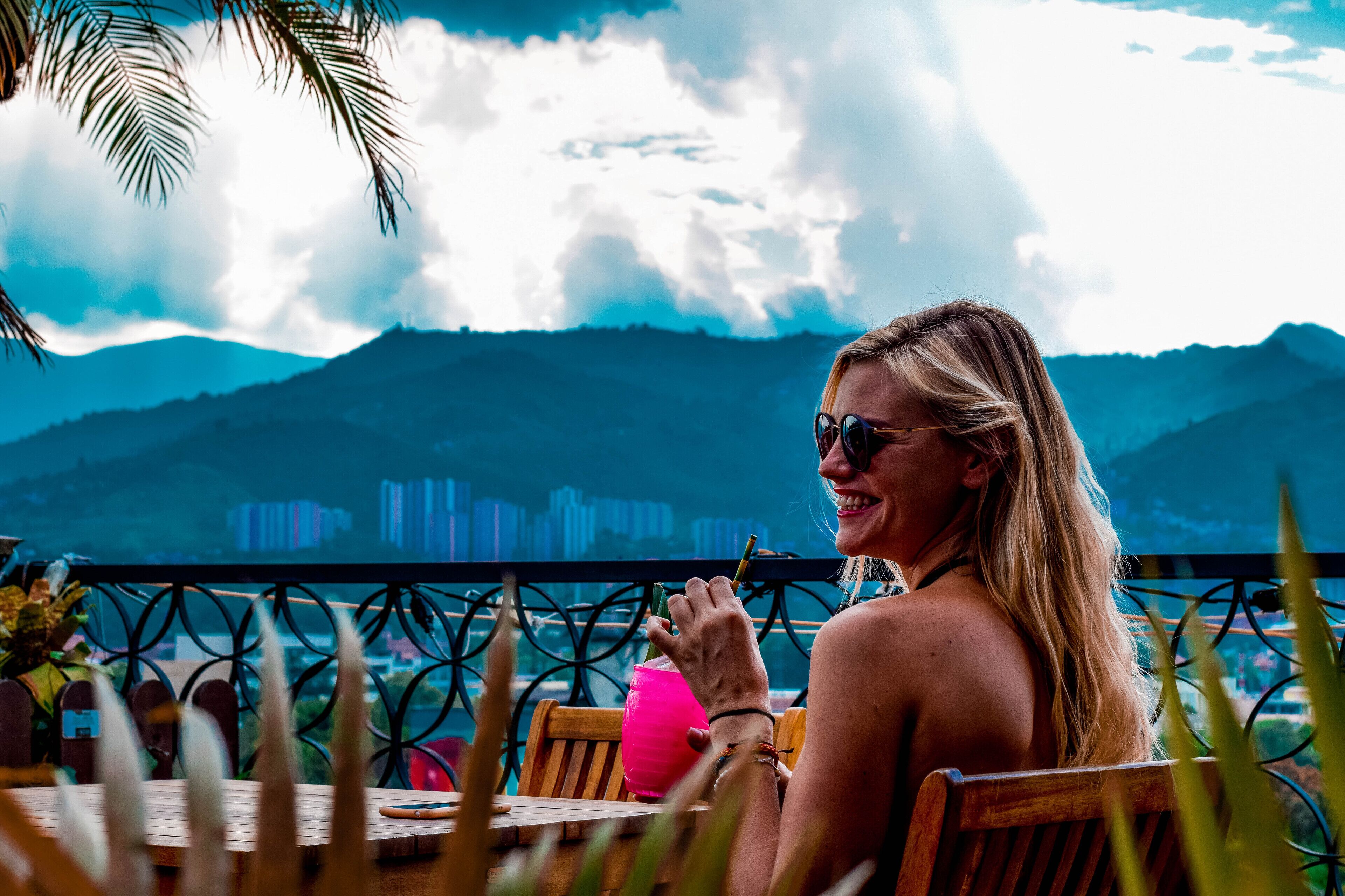 Una persona sentada a una mesa con vistas a montañas y al horizonte de una ciudad.
