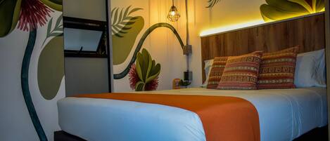 Ein modernes Hotelzimmer mit einem Bett, einem Holz-Kopfschild und einer Wandmalerei mit tropischen Blättern.