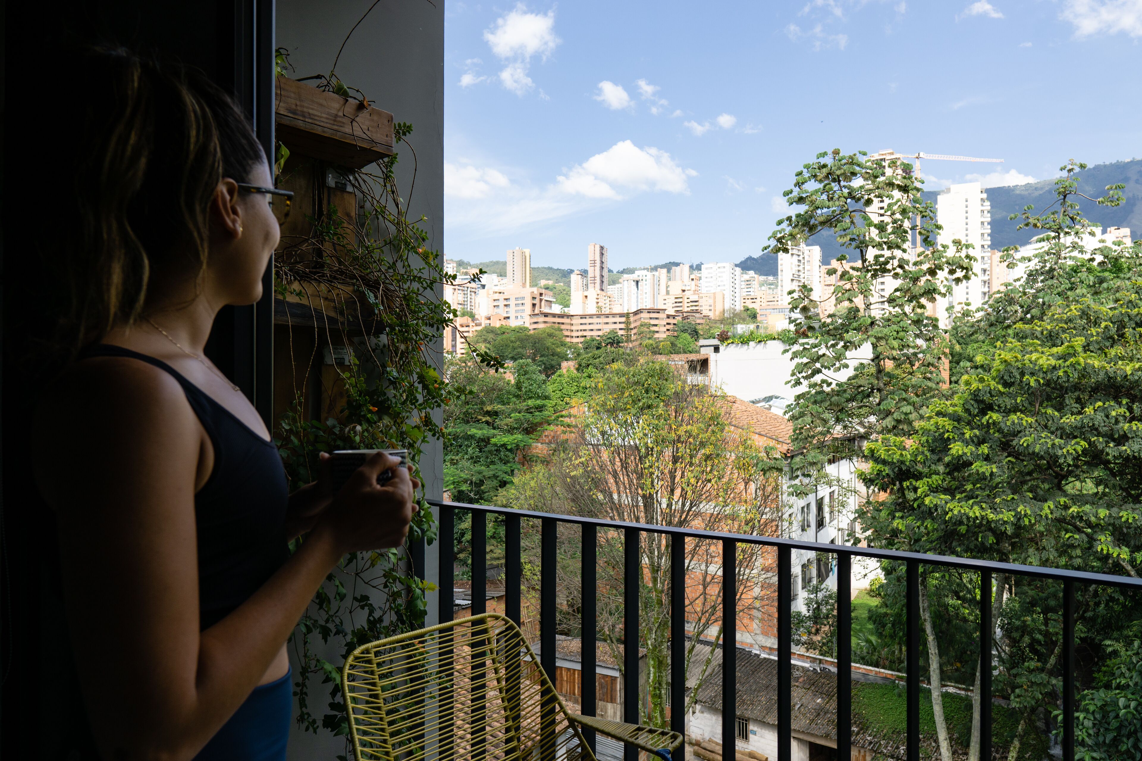 A balcony with a view of a cityscape, including buildings and trees.