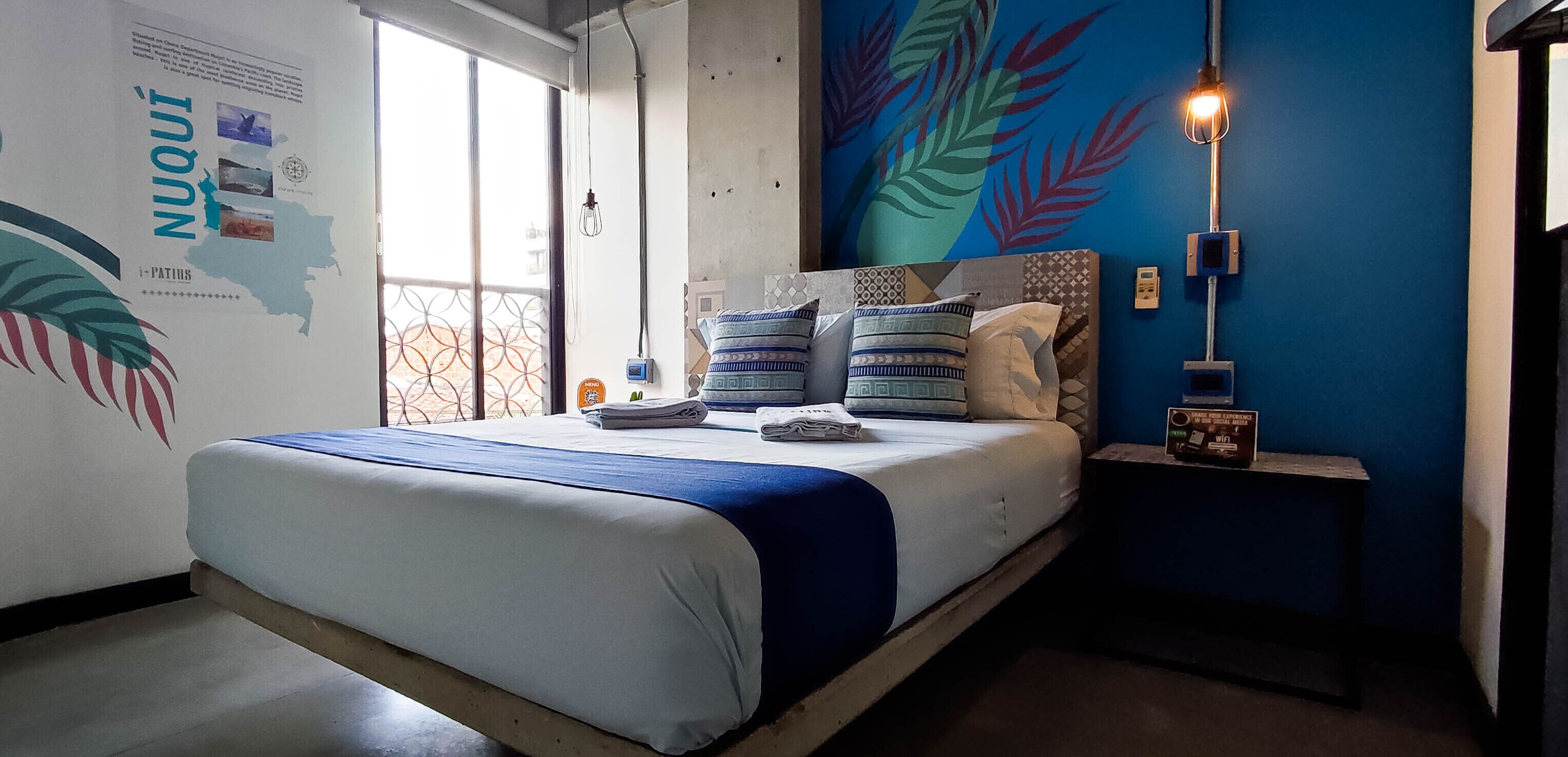 Una camera da letto con un letto, una mappa a muro, un affresco e un comodino con una lampada.