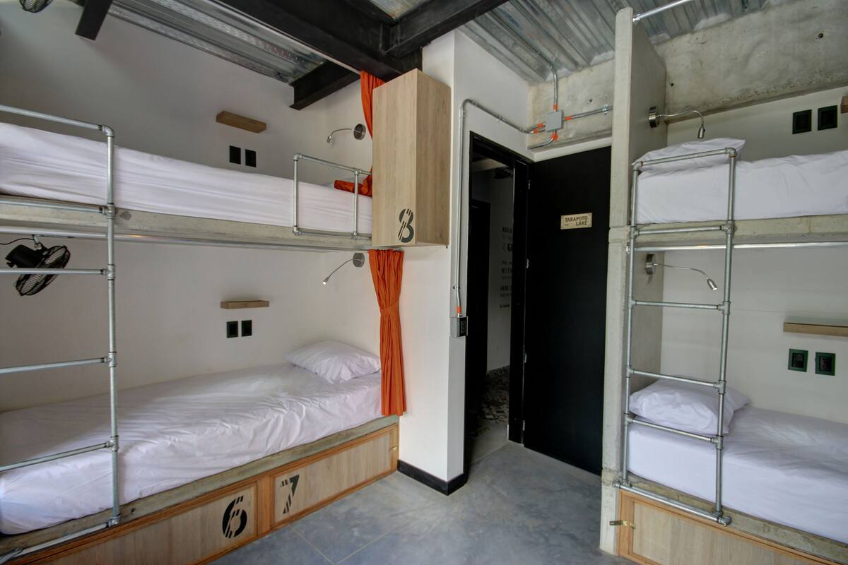 A bunk bed room with a wooden cabinet and a door leading to another room.