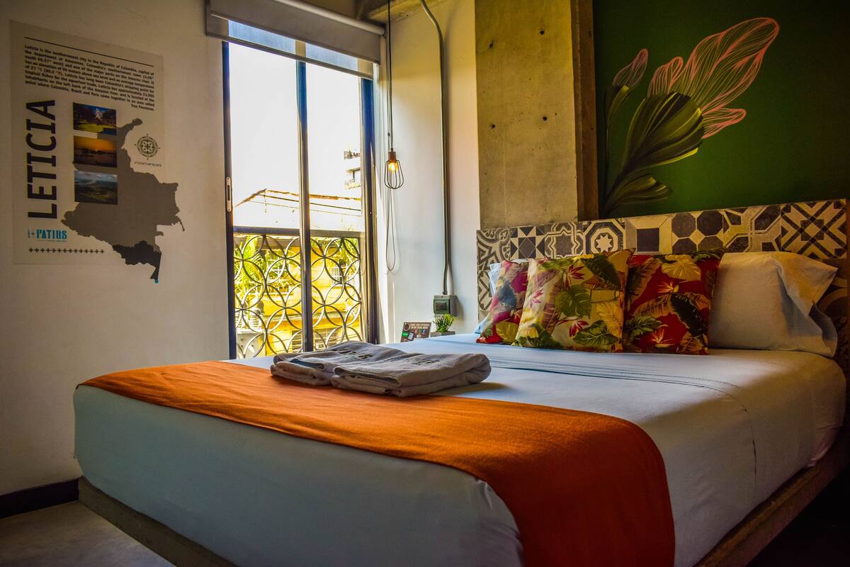 A hotel room with a bed, a map on the wall, and a view of the outside.