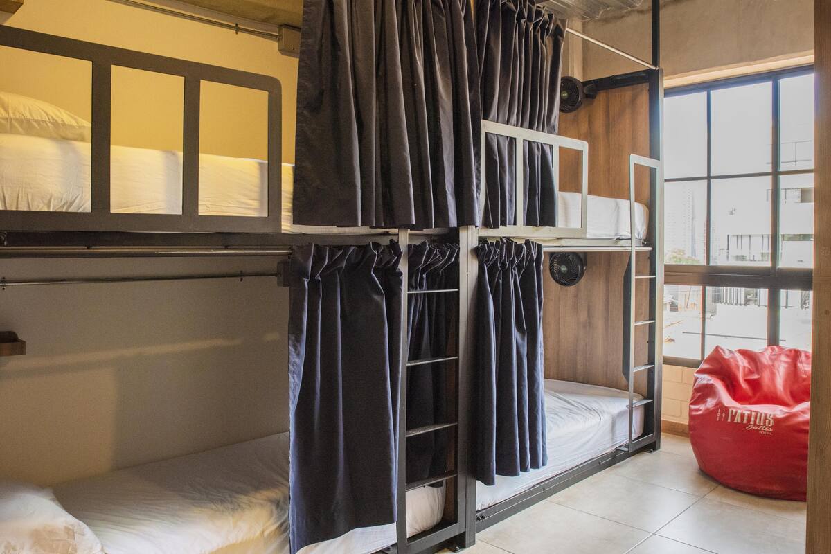 A bunk bed room with curtains, a ladder, and a red bean bag.