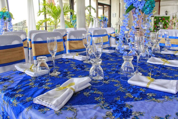 A table set for a formal event with blue and gold tablecloth, white napkins, and clear glassware.