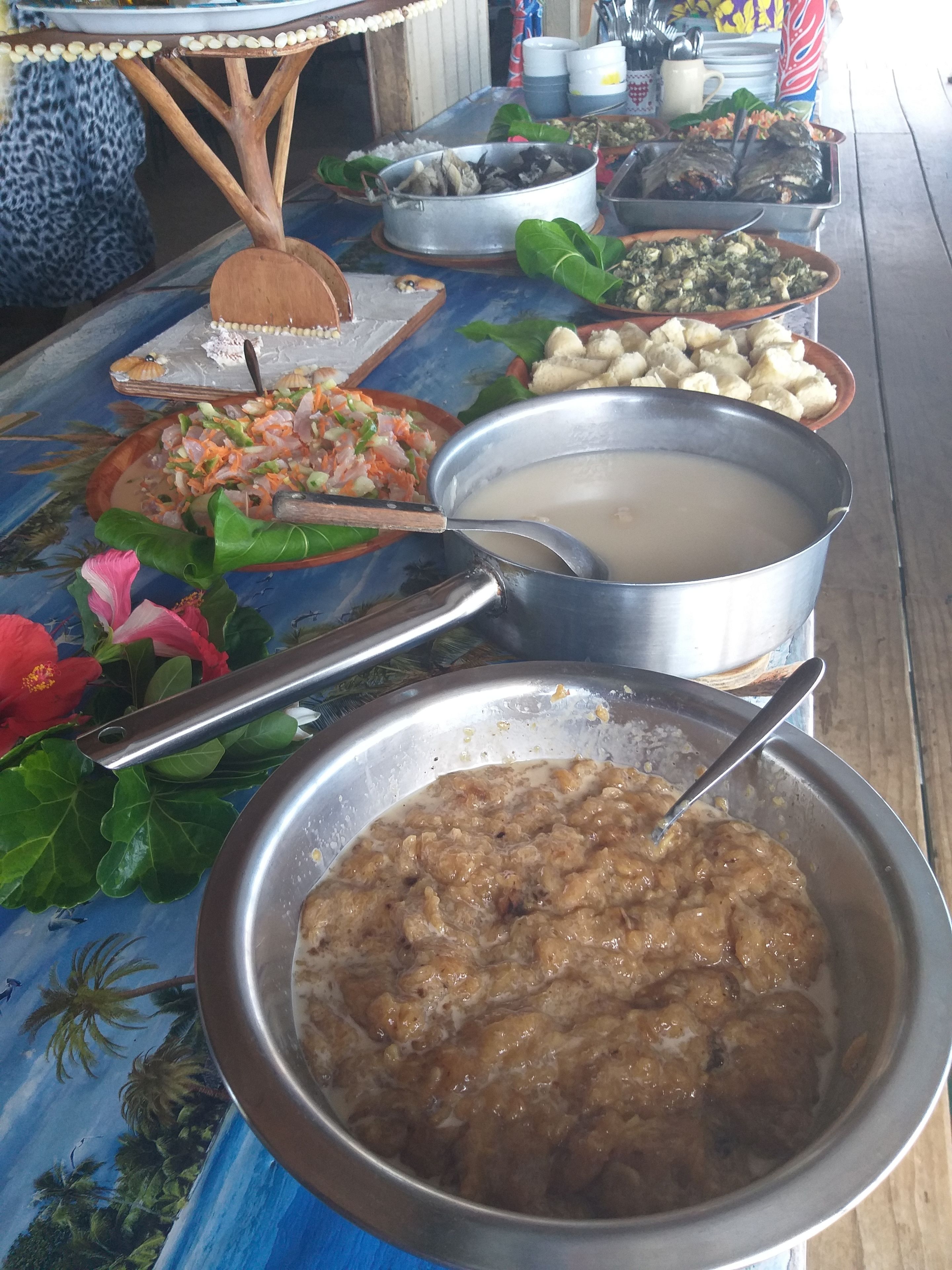 A table with various dishes, including a bowl of soup, a pot of stew, and a plate of salad.