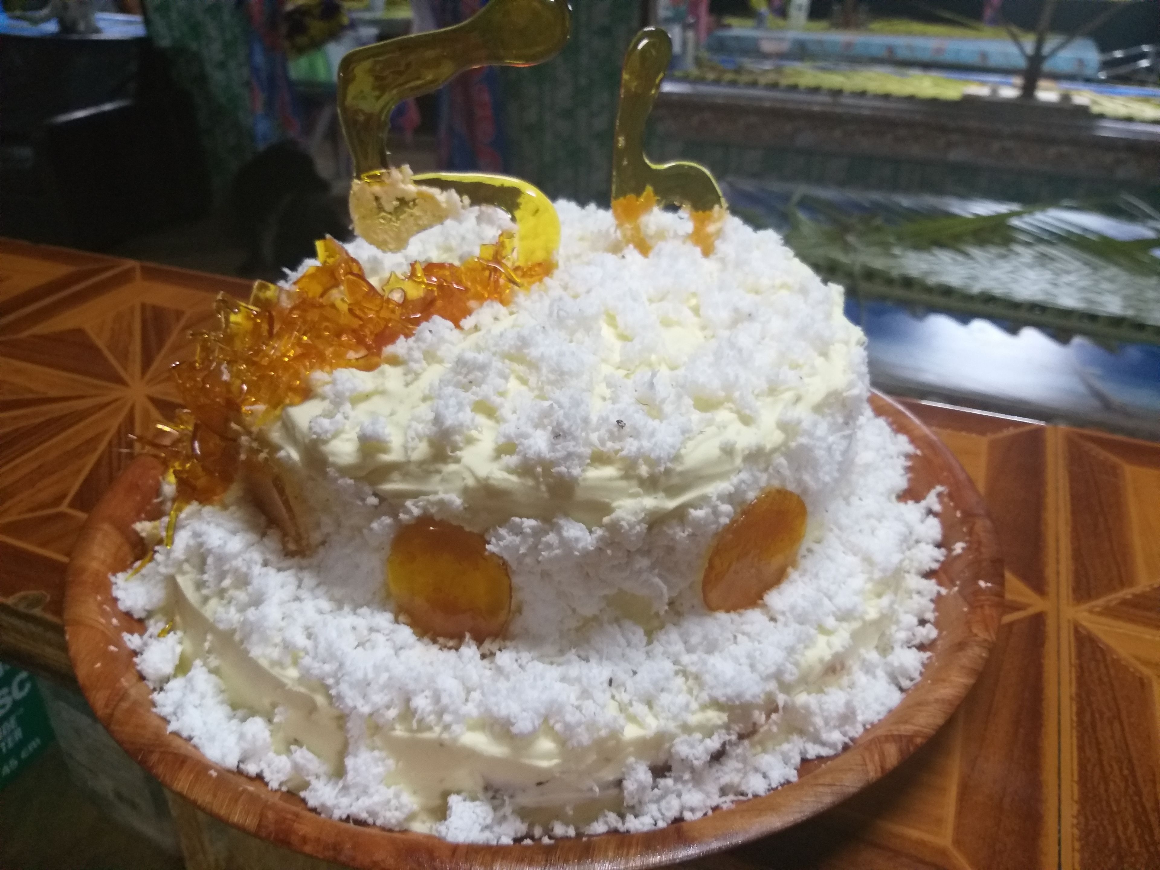 A cake with white frosting and orange decorations on a wooden table.