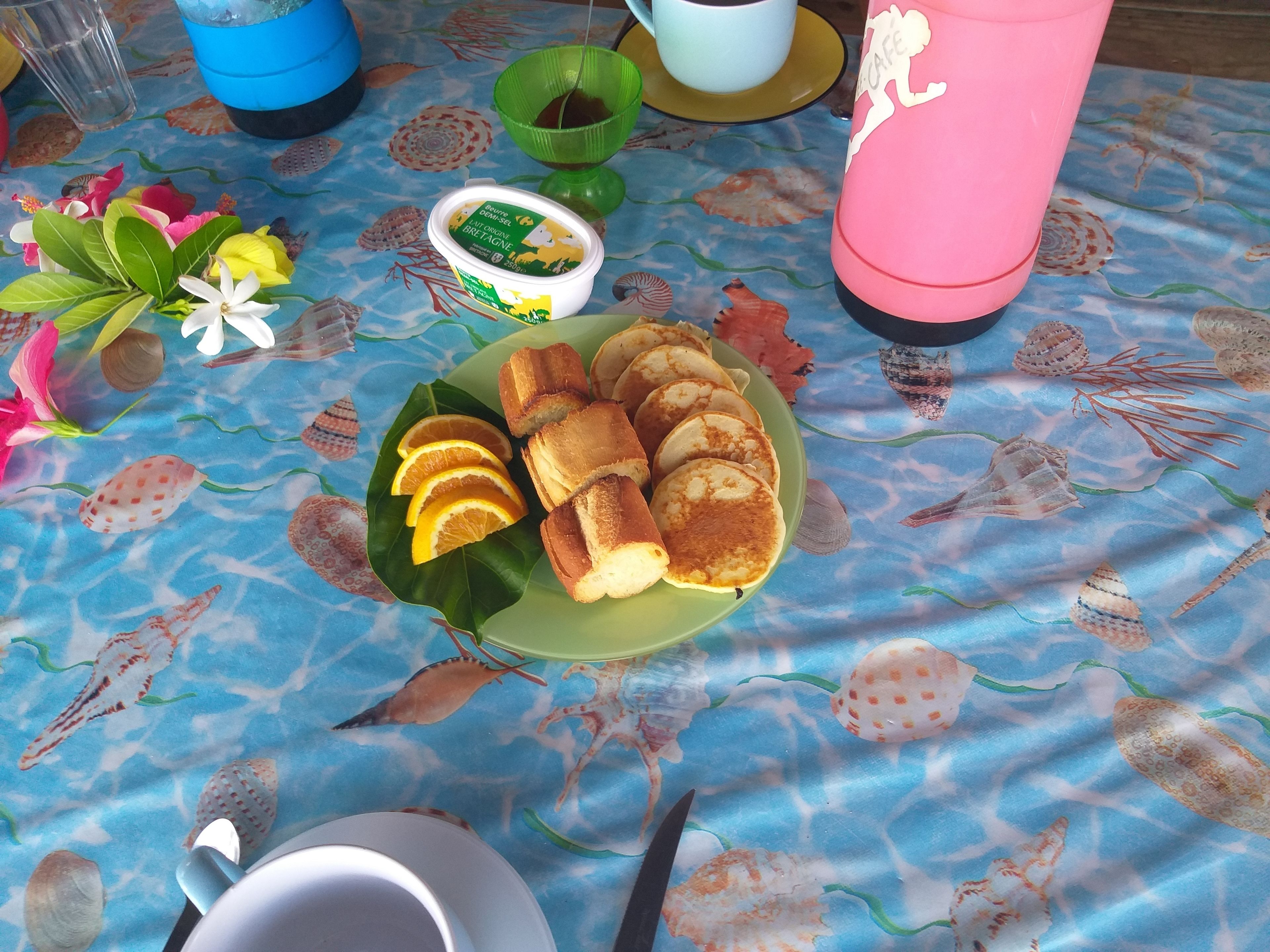 A breakfast table with a plate of pancakes, a cup, and a thermos.