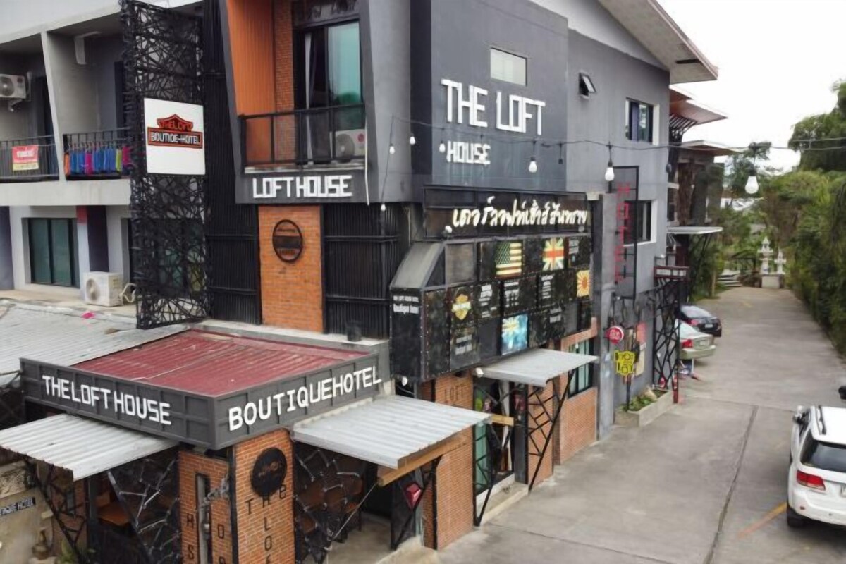 A building with multiple signs including 'THE LOFT HOUSE' and 'BOUTIQUE HOTEL'.