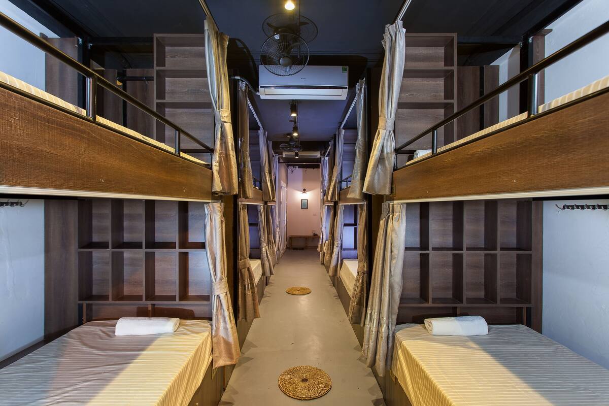A corridor with bunk beds, a central air conditioning unit, and a ceiling fan.