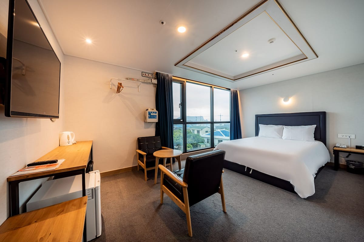 Una habitación de hotel con cama, escritorio, silla y una pequeña mesa.