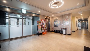 Eine moderne Lobby mit Glastüren, einem Zeitschriftenständer, einem kleinen Kühlschrank und einer Karte an der Wand.