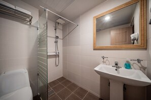 A bathroom with a glass-enclosed shower, a white sink with a mirror above it, and a toilet.