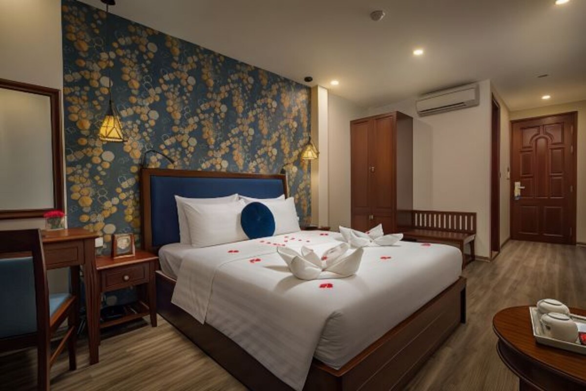 A hotel room with a bed, bedside tables, a desk, and a wardrobe.