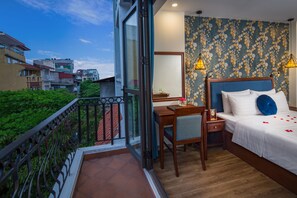 A hotel room with a balcony, a desk, a bed with white bedding, and a patterned wall. - Holiday Emerald Hotel (Hanoi)