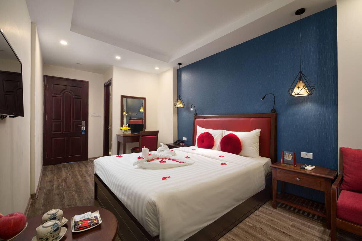 Une chambre d’hôtel avec un grand lit, un bureau, une chaise, une table de chevet et un téléviseur.