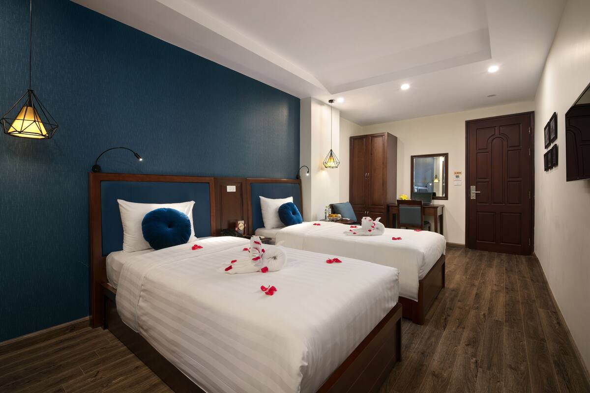 Une chambre d’hôtel avec deux lits, des têtes de lit en bois et un mur d’accent bleu.