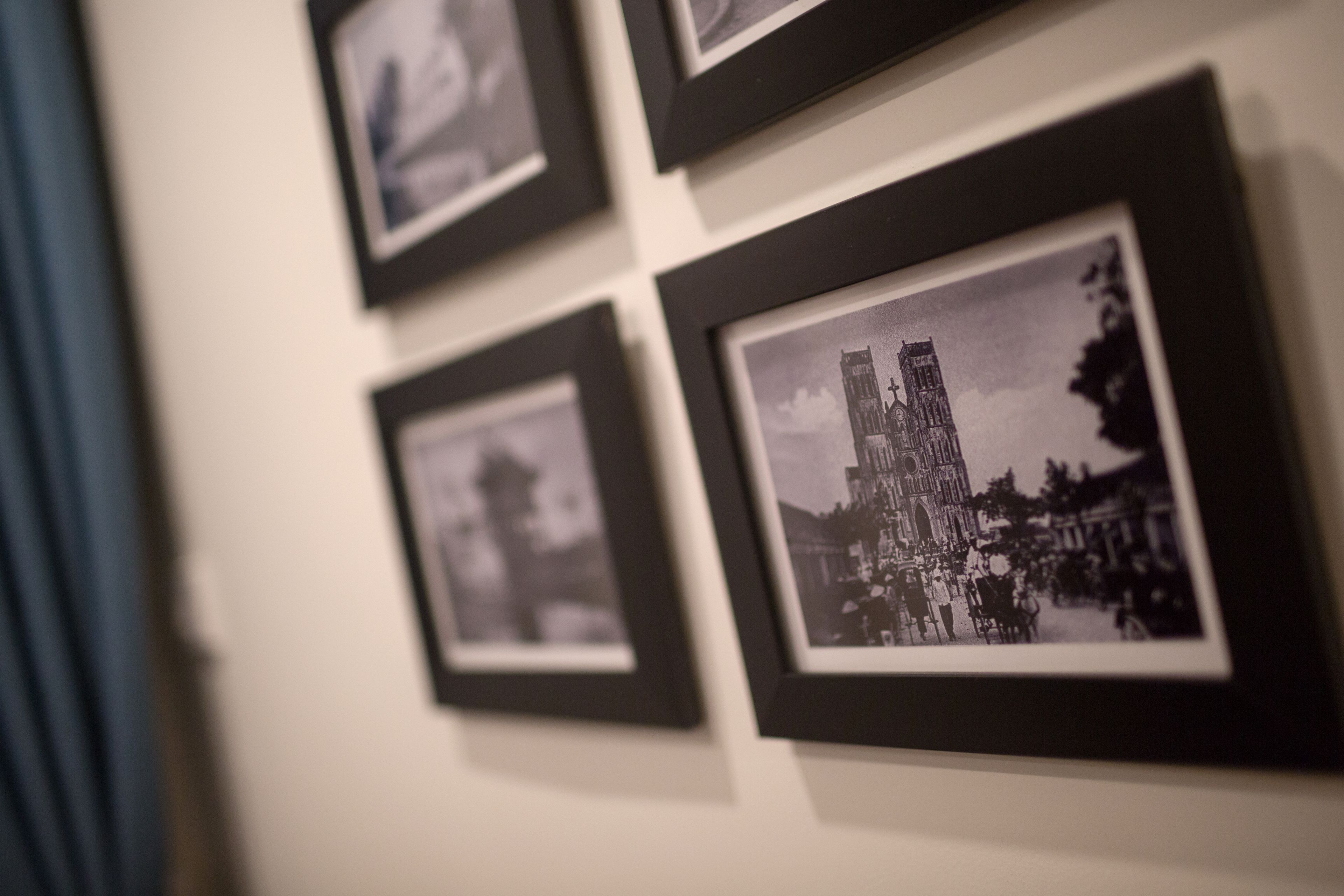 A wall with several framed black and white photographs, including one of a cathedral.