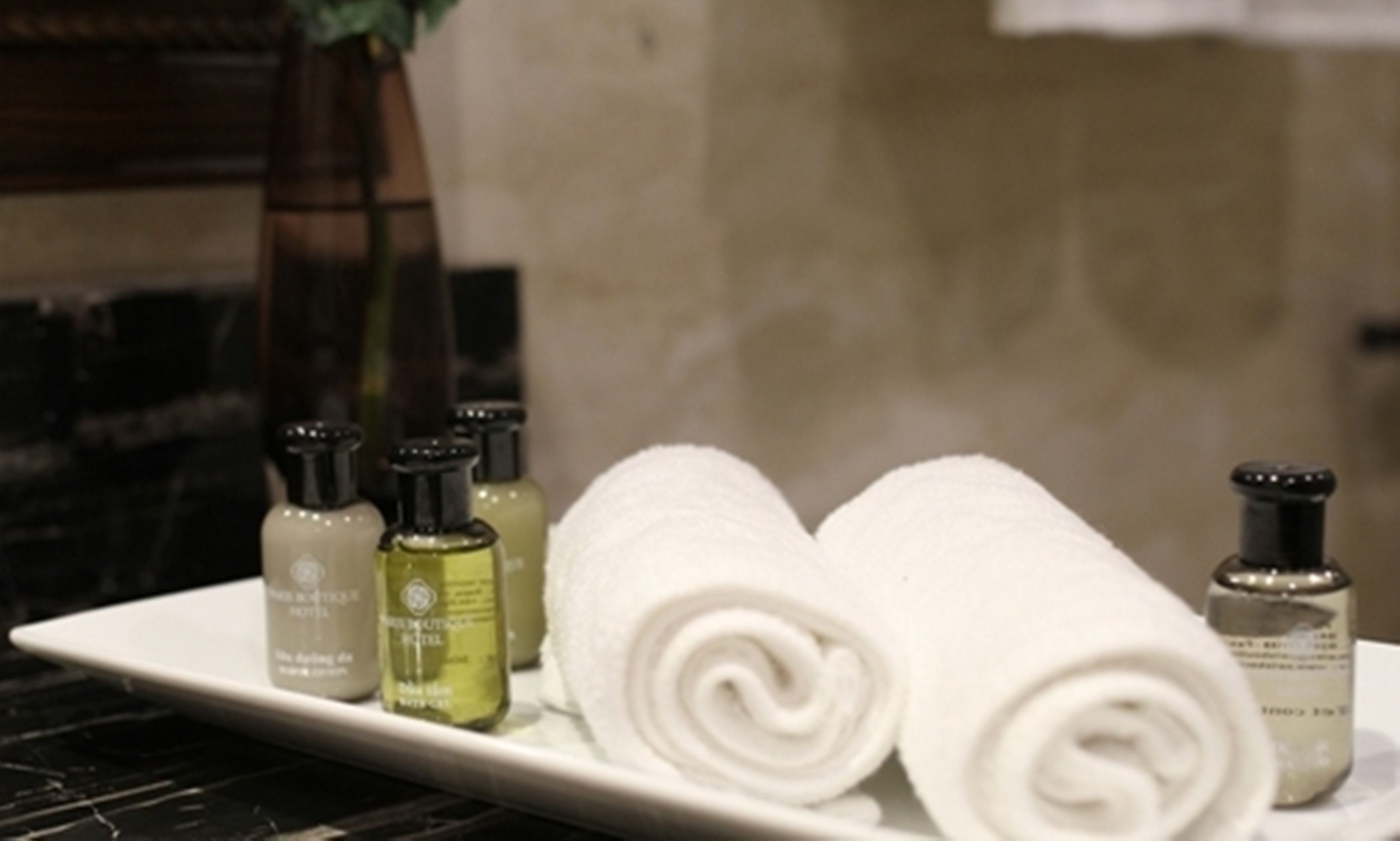 A tray with rolled white towels and several small bottles of toiletries.