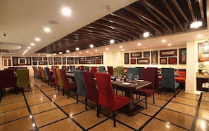 Un restaurant avec des banquettes et des tables, des œuvres d’art encadrées accrochées aux murs et un sol carrelé.