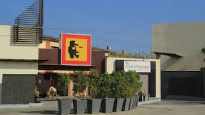 Entrada de un hotel con un gran letrero que presenta un elefante estilizado y un letrero más pequeño que dice 'The One Verenata Hotel'.