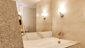 Un baño con bañera de mármol, encimera de granito y espejo.