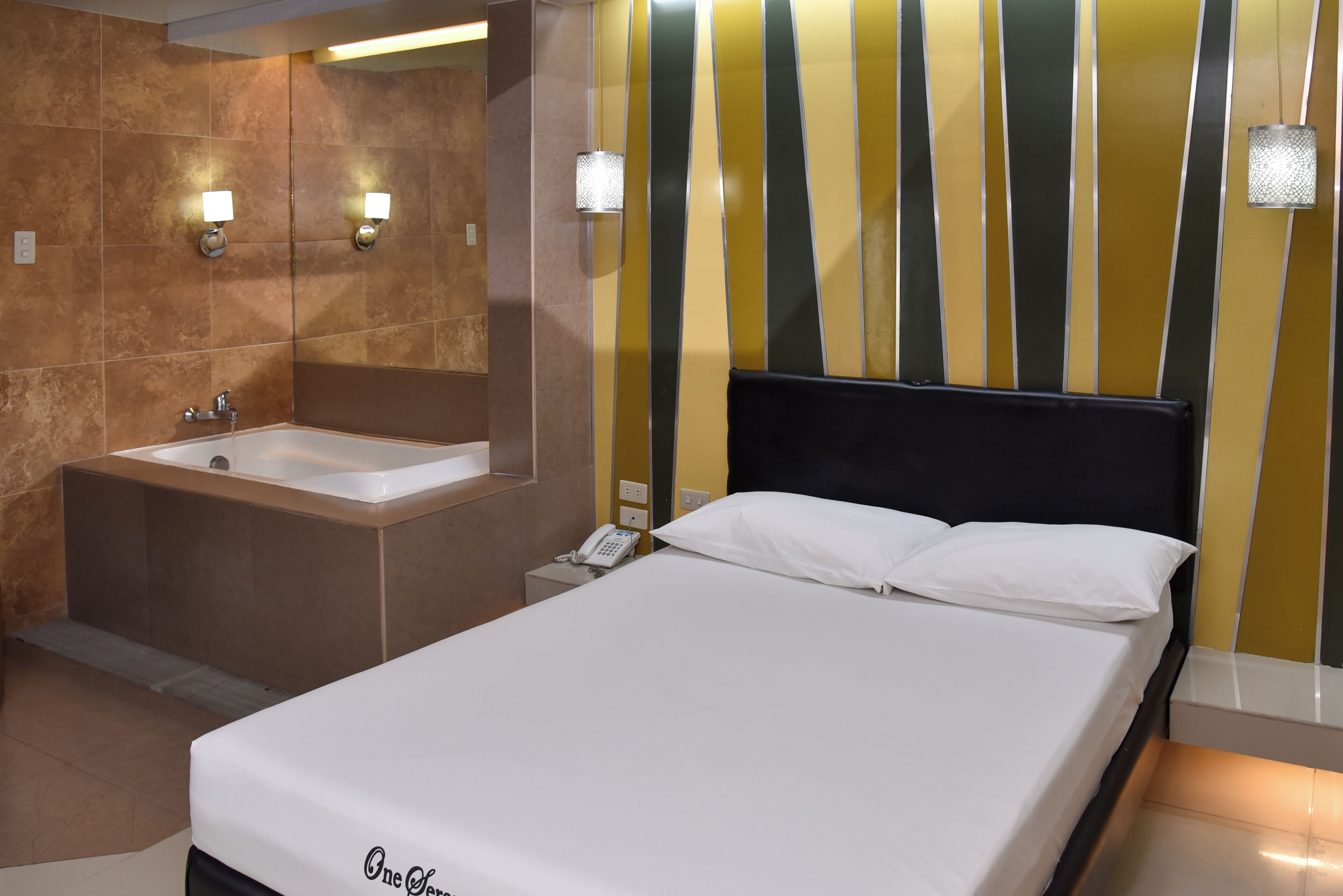 A hotel room with a large bed, a separate bathroom with a bathtub, and a mirror.