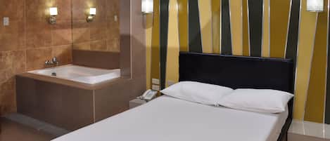 A hotel room with a large bed, a separate bathroom with a bathtub, and a mirror.