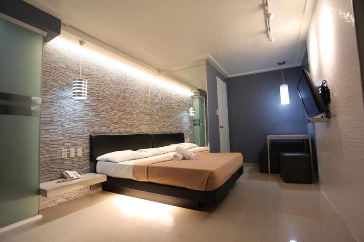 A modern bedroom with a bed, bedside table, and a mirror.